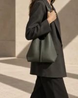 Meridian Spine Shoulder Bag in moss grey worn with a tailored outfit