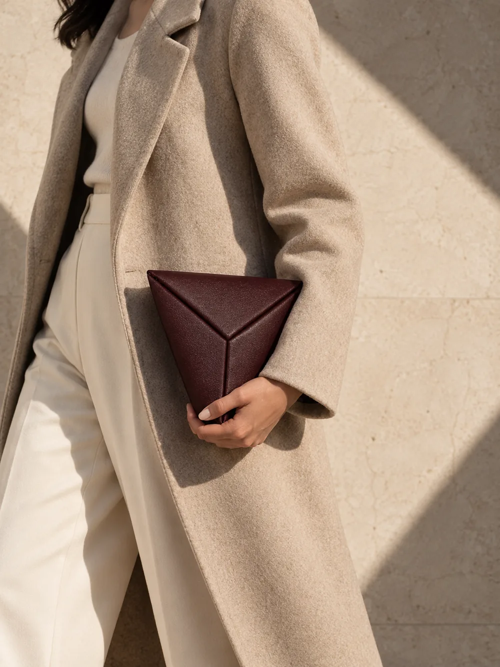 Triad Triangle Clutch in oxblood worn with a tailored outfit