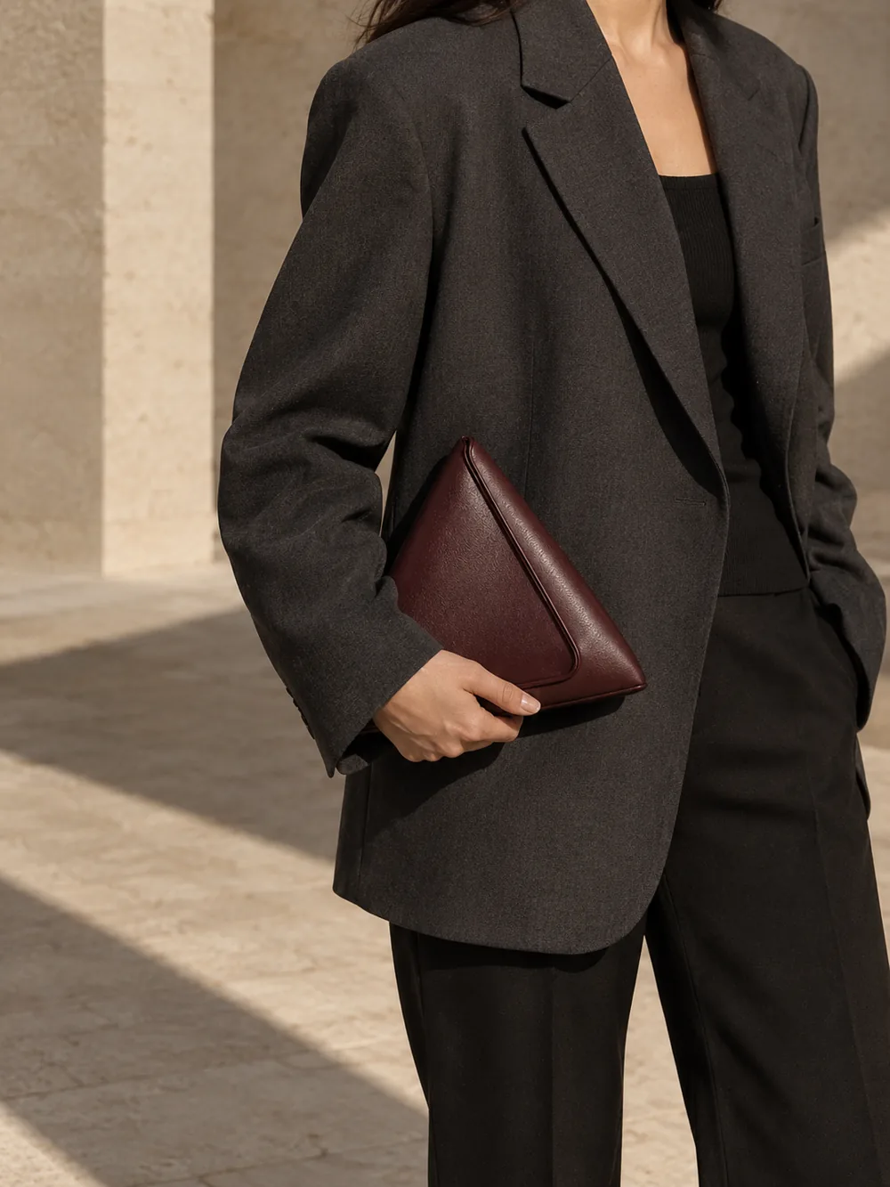 Edgework Triangle Clutch in oxblood worn with a tailored outfit