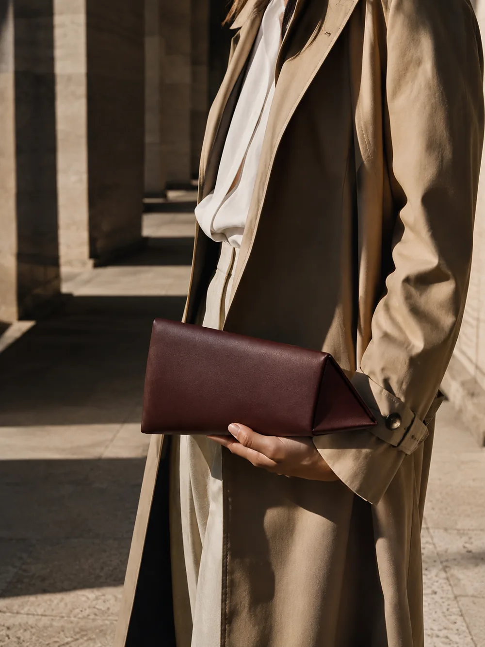 Lucent Wedge Clutch in oxblood worn with a tailored outfit
